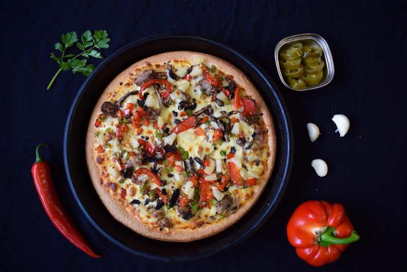 Pizza topped with mushroom, red capsicum and olives